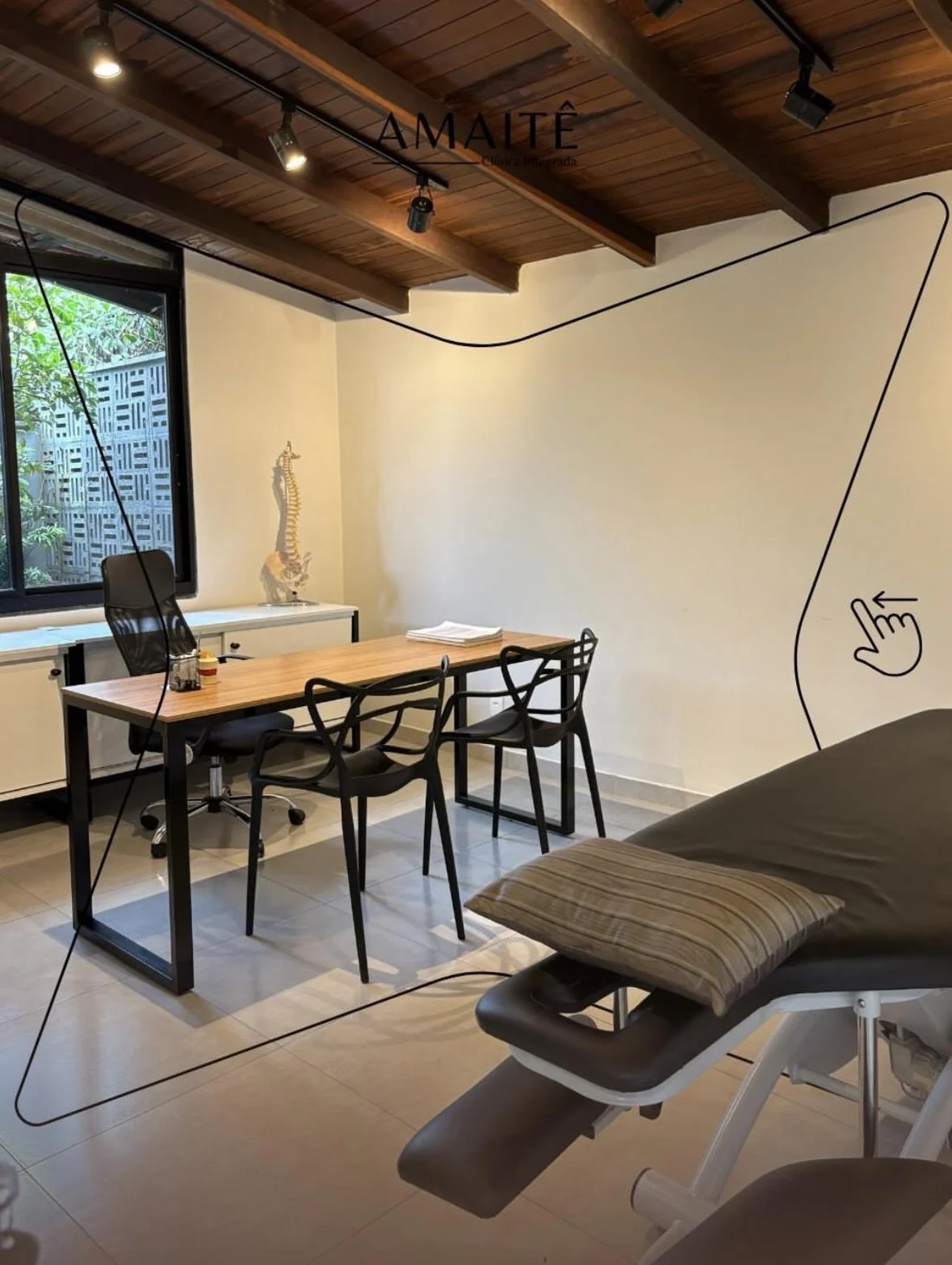 Sala de atendimento da Amaitê Clínica Integrada com mesa de madeira e modelo anatômico de coluna