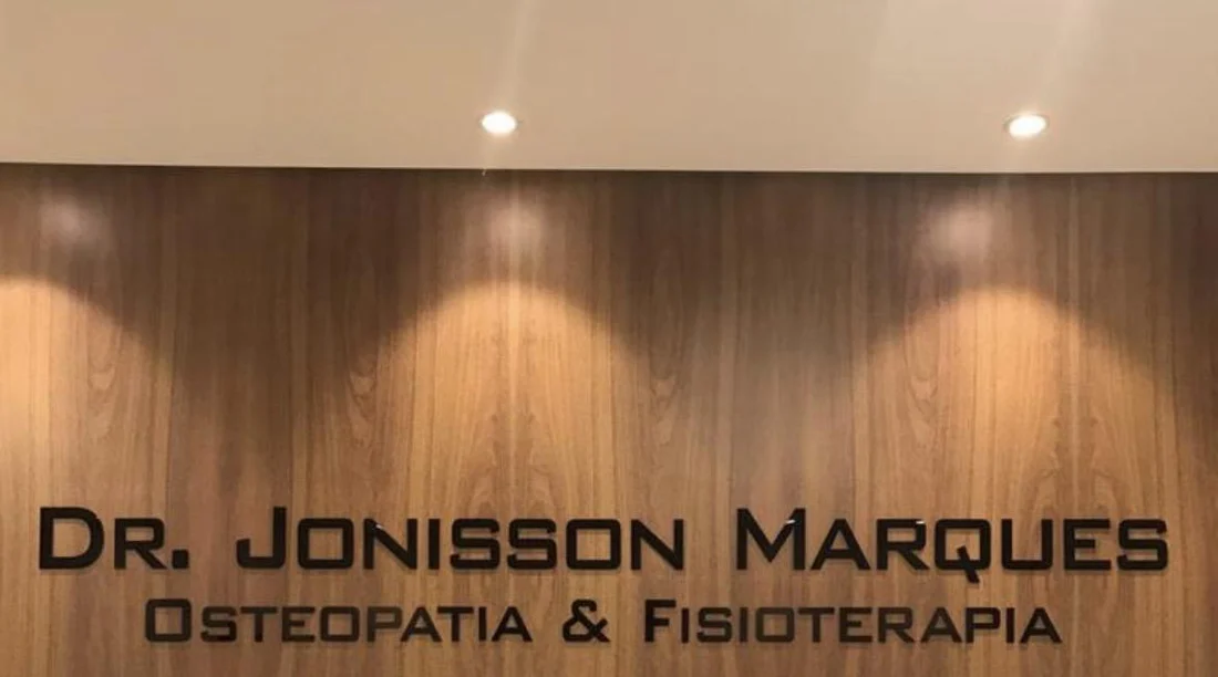 Parede de madeira com o nome Dr. Jonisson Marques, Osteopatia e Fisioterapia